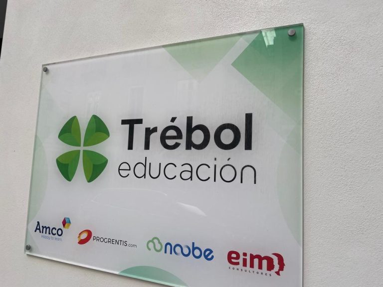Tablica informacyjna firmy „Trébol educación” z logotypem zielonej czterolistnej koniczyny. Na dole widoczne logotypy partnerów: Amco, PROGRENTIS.com, niobe oraz eim consultores.